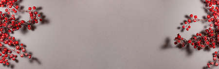 Banner of red berries on the branch Christmas decoration on gray background on the left and right side. Top view flat lay. Holidays concept with copy spaceの写真素材