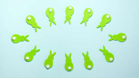 Green rabbits bunnies converge and diverge on blue background with copy space in centre of the frame. Flat lay top view. Easter conceptの写真素材