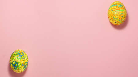 Yellow and green easter eggs on pink background at the top and bottom with space for text. Flat lay top view. Easter conceptの写真素材
