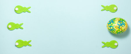 Green rabbits and easter eggs banner on blue background. Flat lay top view with copy spaceの写真素材