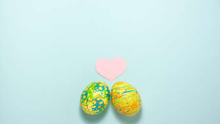 Two easter colorful eggs roll out to each other on blue background. Flat lay with copy spaceの写真素材