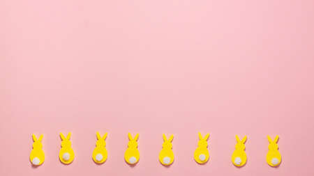 Yellow velvet bunnies with white tails on bright  pink background at the bottom with copy space. Flat lay top view. Happy Easter concept templateの写真素材
