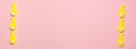 Banner of yellow velvet bunnies on pink background on the left and right side with copy space. Flat lay top view. Easter conceptの写真素材