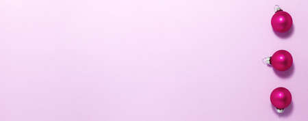Pink Christmas balls on purple background on right side. Flat lay top view with copy space. Holidays conceptの写真素材
