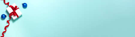 Banner of gift white paper box with a red ribbon bow and blue christmas balls on blue background with copy space. Flat lay top view Christmas winter holidays  anniversary presents conceptの写真素材