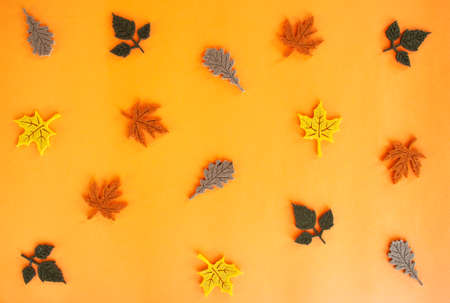 Beautiful autumn flat lay pattern of felt decoration leaves of oak and maple of yellow red orange green and brown colors on orange background. Holidays concept with copy space.の写真素材