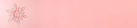 Banner of transparent snowflake with glitter at the tips on a bright pink background on the left side. Christmas concept lay lay top view with copy spaceの写真素材