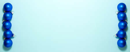 Blue Christmas balls on blue background on left and right side. Flat lay top view with copy space. Holidays concept.の写真素材