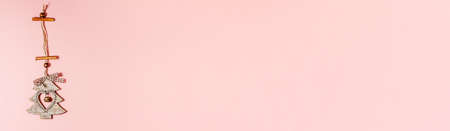 Banner of flat lay of wooden christmas decoration tree with heart inside it and jingle bell on pink. Christmas holidays concept from above with copy spaceの写真素材