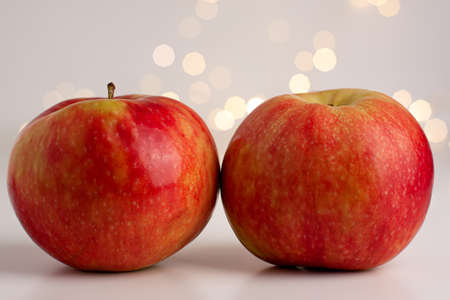 Close up of two red yellow apples on bright background with yellow gold bokeh behind. Healthy organic food, autumn mood and still life concept with copy spaceの写真素材