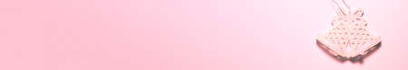 Banner of bright pink glossy glitter jingle bells on pink background on the left side. Flat lay New...