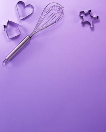 Steel whisk house men and heart shaped cutter flat lay top view. Confectionery cooking concept with copy space on bright purple paper background. National cooking dayの写真素材