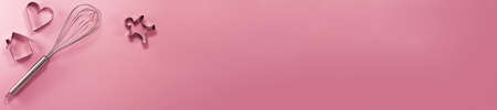 Banner of steel whisk house men and heart shaped cutter flat lay top view. Confectionery cooking concept with copy space on bright pink paper backgroundの写真素材