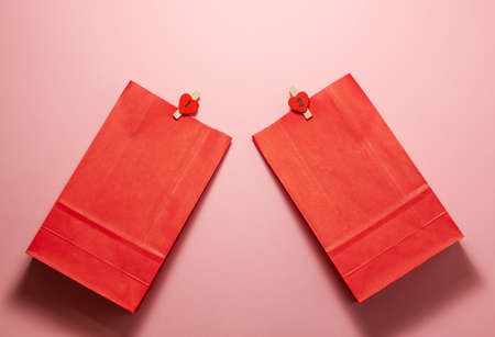 Flat lay top view of red paper gift bags with little tweezers with hearts on them on the bottom....