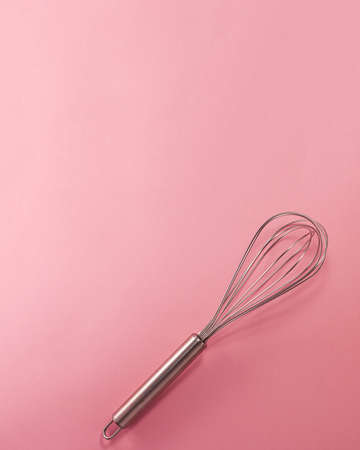 Steel whisk flat lay top view. Confectionery cooking concept with copy space on bright pink paper backgroundの写真素材