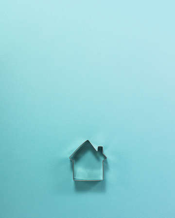 Steel house shaped cutter for cookies from above. Flat lay top view. Confectionery cooking concept with copy space on bright blue paper background.の写真素材