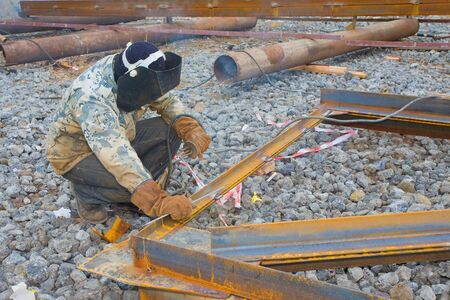 Welder in mask welding metal construction on open air.の写真素材