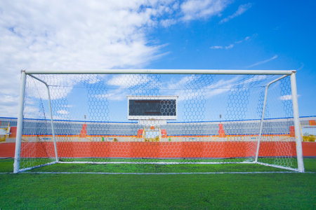 Football field with goal and tablo on blue skyの写真素材