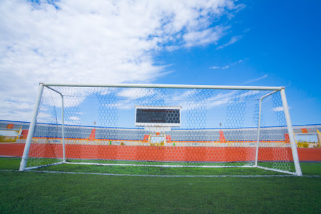 Football field with goal and tablo on blue sky