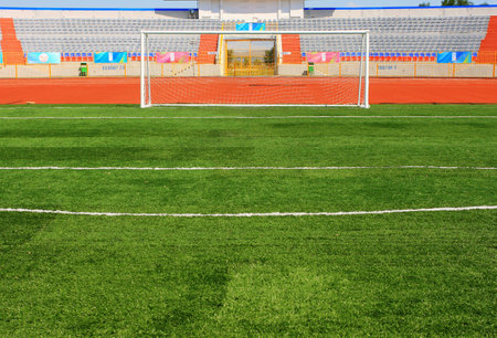 Football field with goal and tablo on blue sky