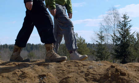 Close up legs of couple walking on a sand near the forest. Early spring, sunny weather. Bright blue...