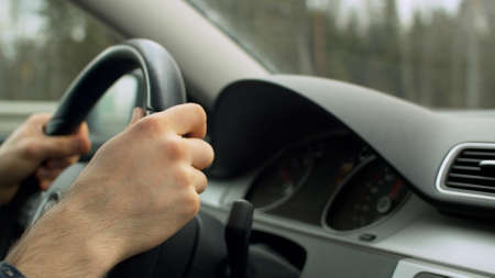 Close up mans hands on the steering wheel of moving car. Drivers point of view, POV. Dashboard