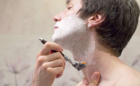 Extreme close-up man's face and neck in soap foam shaving with a shaving machine. Daily face careの写真素材