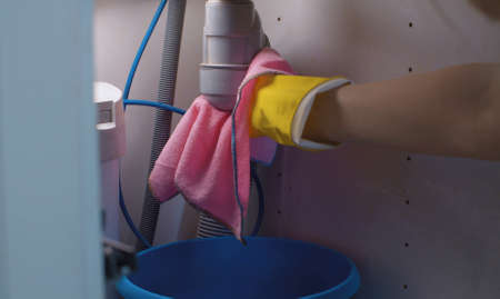 Close up woman's hands screwing the current syphon and wiping the water with a rag. Water flowing...