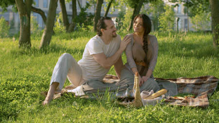 Beautiful couple in love hugging and kissing. People on picnic in the park. Wide shot. Love, pleasure, relaxation and togetherness conceptの写真素材