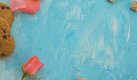 Close up pink rose, raw sugar and cookies on a blue background. Macro shooting. Top viewの写真素材