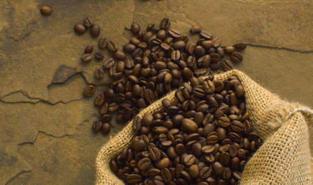 Close-up of roasted coffee beans in a burlap jute sack on the natural stone background. Top view.の写真素材