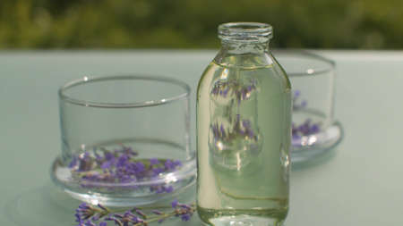 Close up lavender flowers in glass jars and base oil on the table in the garden. Healing herbs....