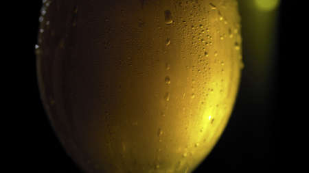 Close up cold beer on dark background. Misted glass of sparkling gold drinkの写真素材