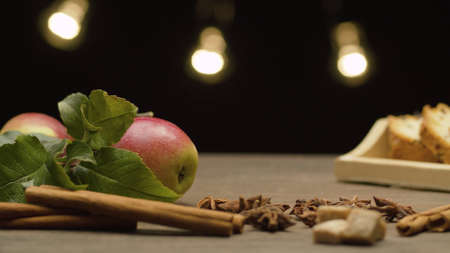 Closeup fresh apples with leaves and spices on the table. Blurry lights on black background. Healthy eatingの写真素材