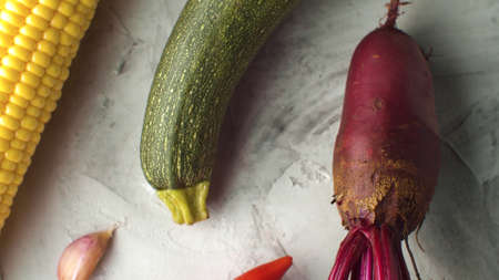 Close up vegetables on the table - fresh beets with leaves, garlic, zucchini and ear of corn on white backgroundの写真素材