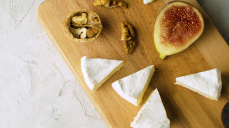 Macro shot camembert, walnuts and halves of fig on a wooden cutting board. Healthy fresh food conceptの写真素材