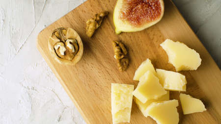 Macro shot cheese, walnuts and half fig on a wooden cutting board. Healthy fresh food conceptの写真素材