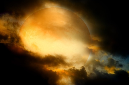 A dark night brings a bright, amber moon alive with puffy hazy clouds.の写真素材
