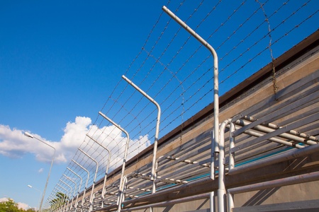 Barbed wire fence against the blue skyの写真素材