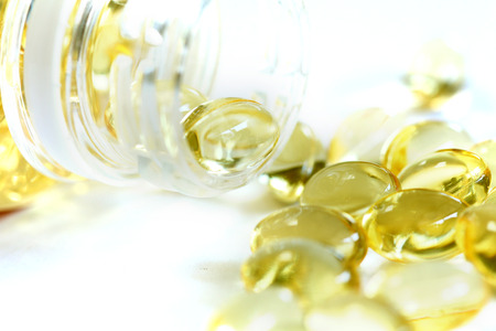Omega 3 fish oil capsules out open container on white background
