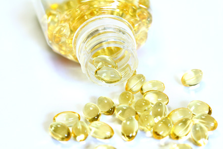 Omega 3 fish oil capsules out open container on white backgroundの写真素材