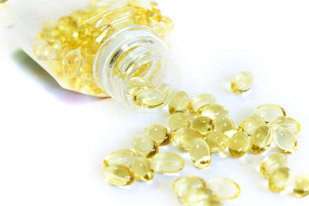 Omega 3 fish oil capsules out open container on white backgroundの写真素材