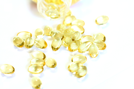 Omega 3 fish oil capsules out open container on white backgroundの写真素材