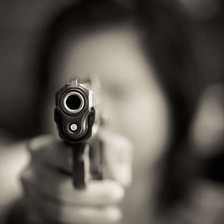 young woman holding a gunの写真素材
