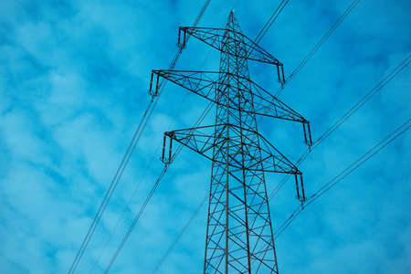 Photo depicting one high-voltage powerful electricity tower with wires on cloudy blue moody evening sky. Europe.の写真素材