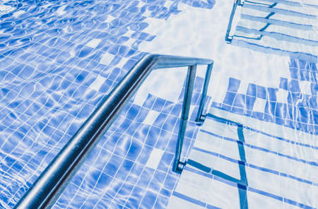 Swimming pool metal staircase in the water. Pool stairs close up, nobody.の写真素材