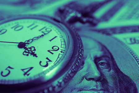 Old pocket watch with American 100 dollar banknotes money with Franklin president portraiture, macro view. Time and business concept.の写真素材