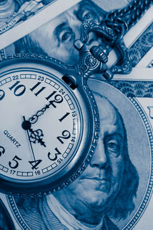 Old pocket watch with American 100 dollar banknotes money with Franklin president portraiture, macro view. Time and business concept.の写真素材