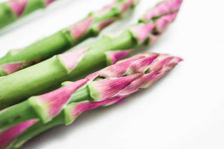 Fresh green asparagus sprout tops, closeup. A bunch of three asparagus stems, isolated on white background, macro.の写真素材