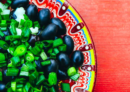 Traditional decor, bulgarian dish with national ornament. Black olives with onion, Balkan restaurant.の写真素材